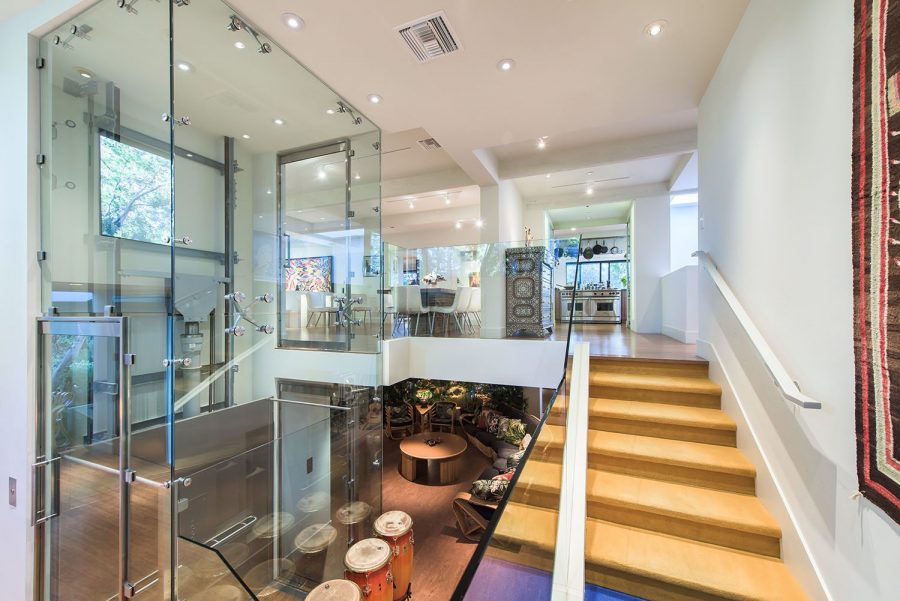 Image shows mezzanine accessible via lift. Stylish glass elevator and staircase providing access to mezzanine floor in celebrity home. Mezzanine Elevator Inspiration.