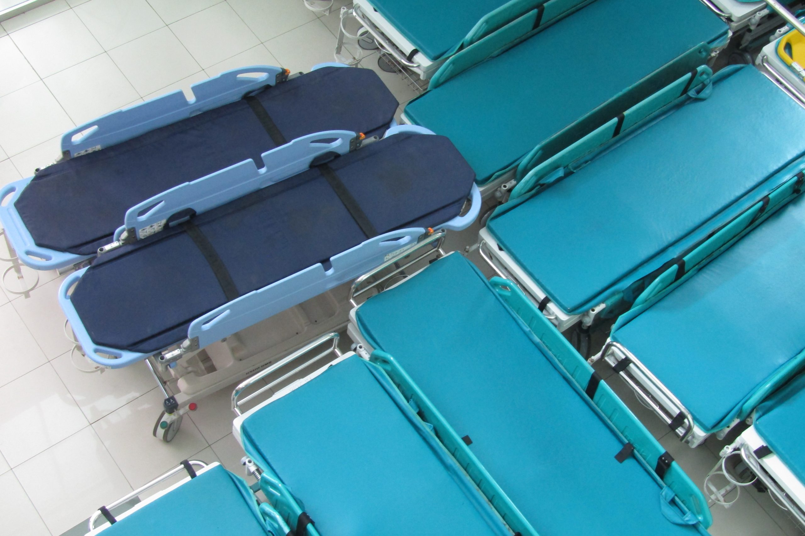 blue ambulance stretcher beds are grouped together in a hospital room.