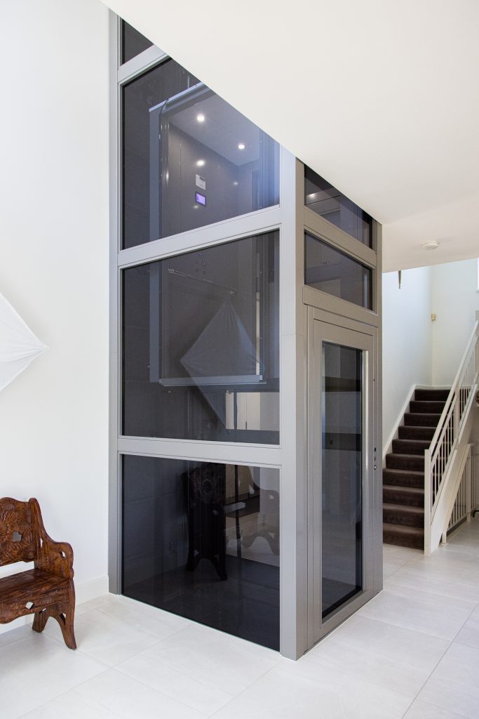 a metal glazed lift shaft protrudes from the white melbourne living room.