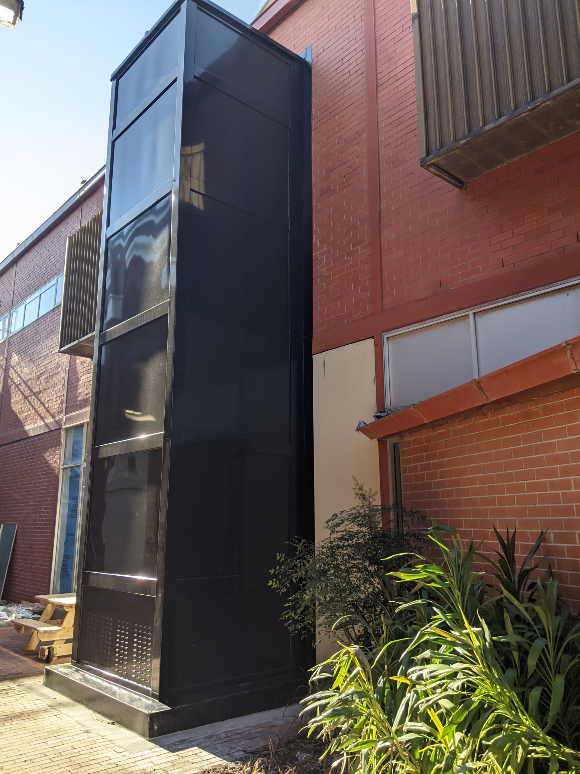 an black metal structure elevator attached to the exterior wall of a building