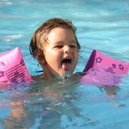 child playing in water with armbands