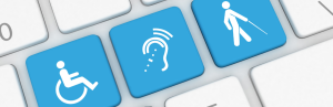 A keyboard with three blue keys featuring white accessibility icons: a wheelchair, an ear with sound waves, and a person using a cane.