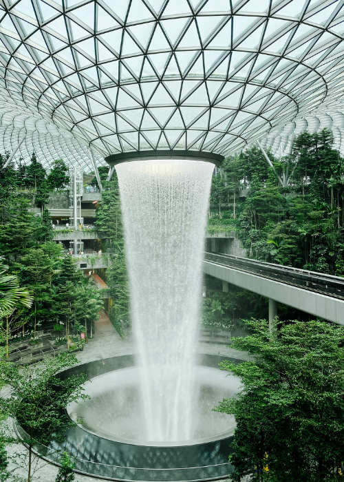 Indoor waterfall surrounded by lush green trees.