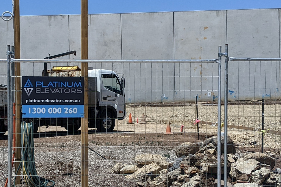 Construction site with Platinum Elevators truck and sign.