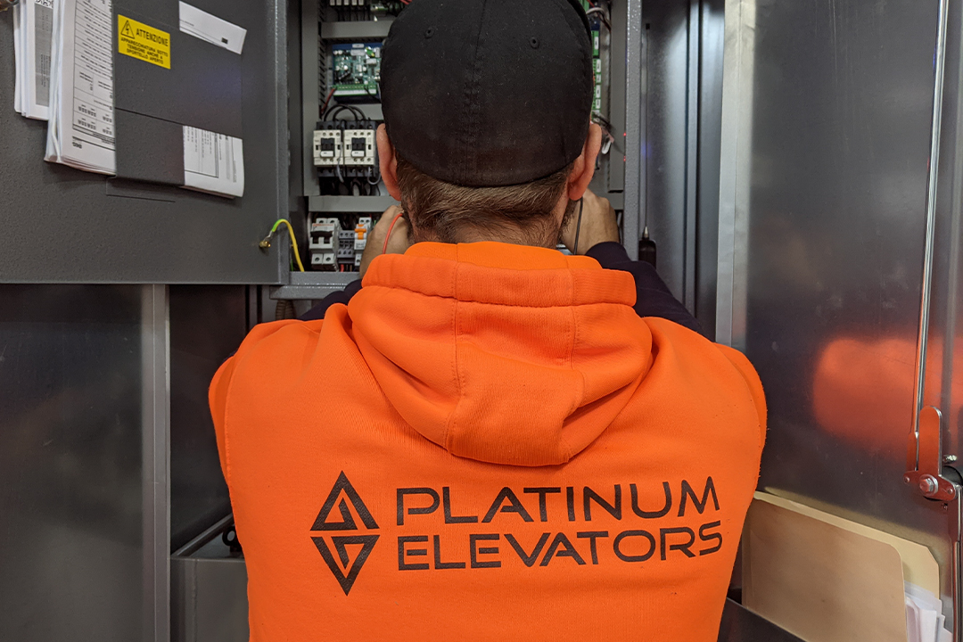 Technician repair elevator control panel with tools.