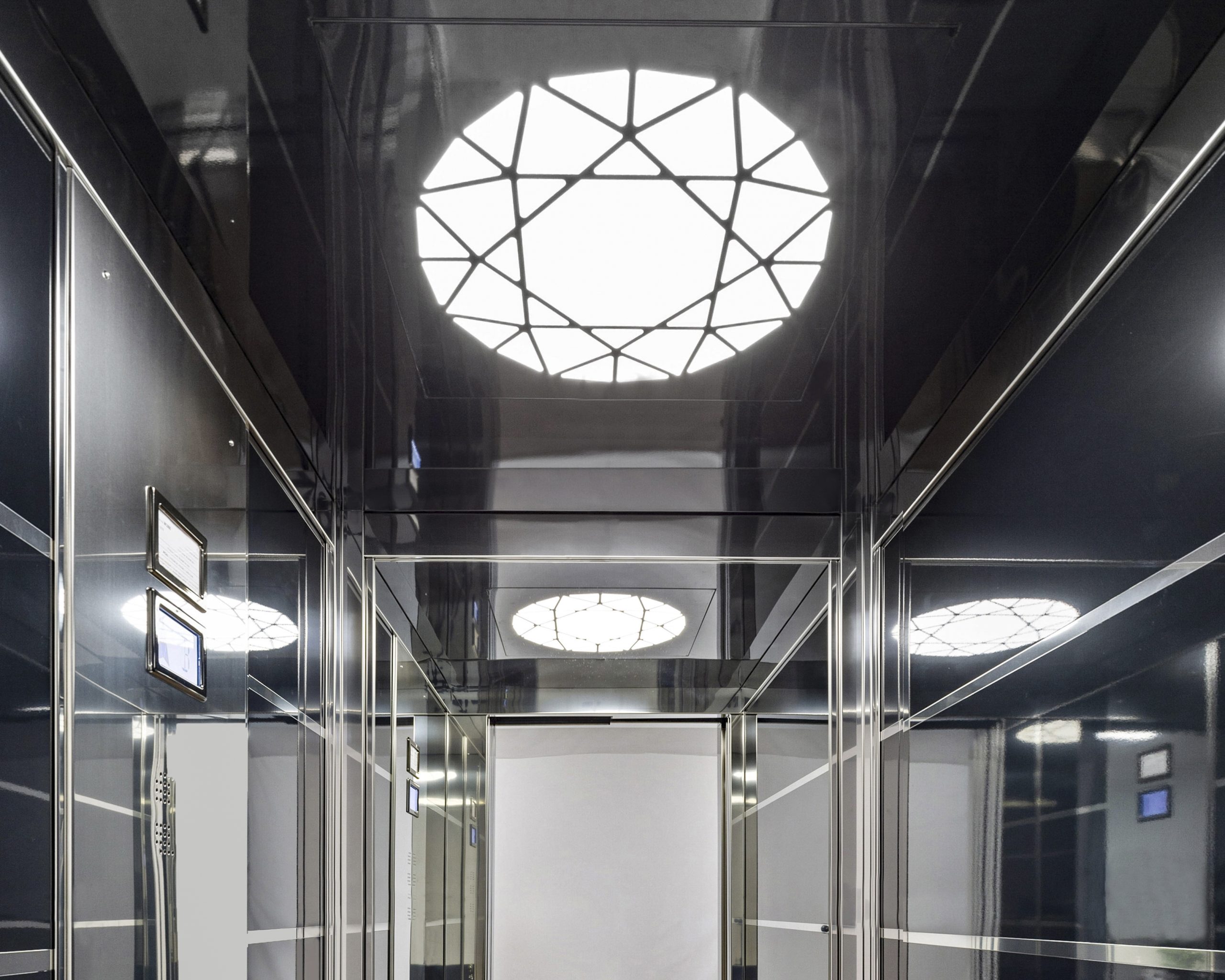 Modern lift interior with mirrored walls and lighting.
