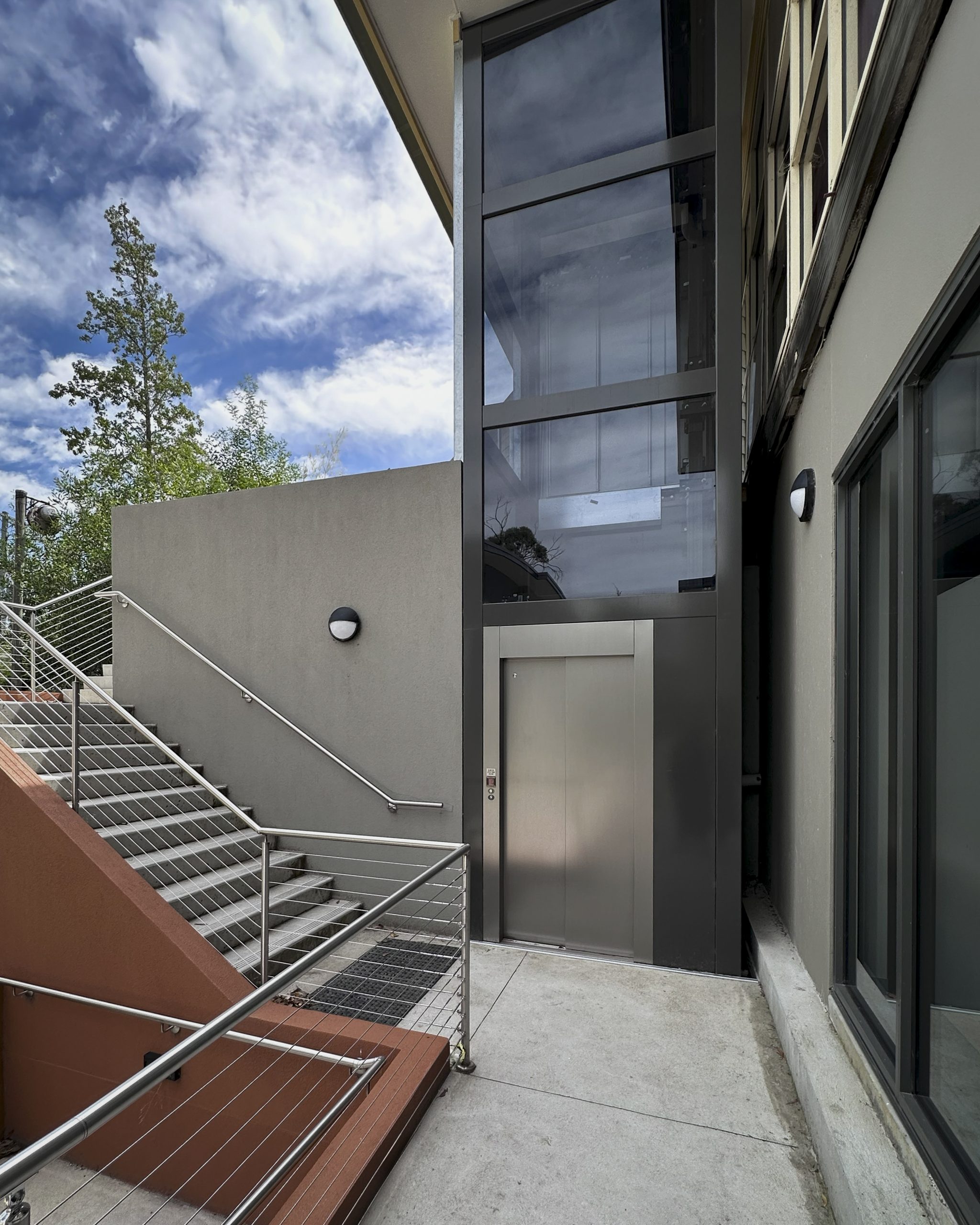 Outdoor lift beside modern building staircase