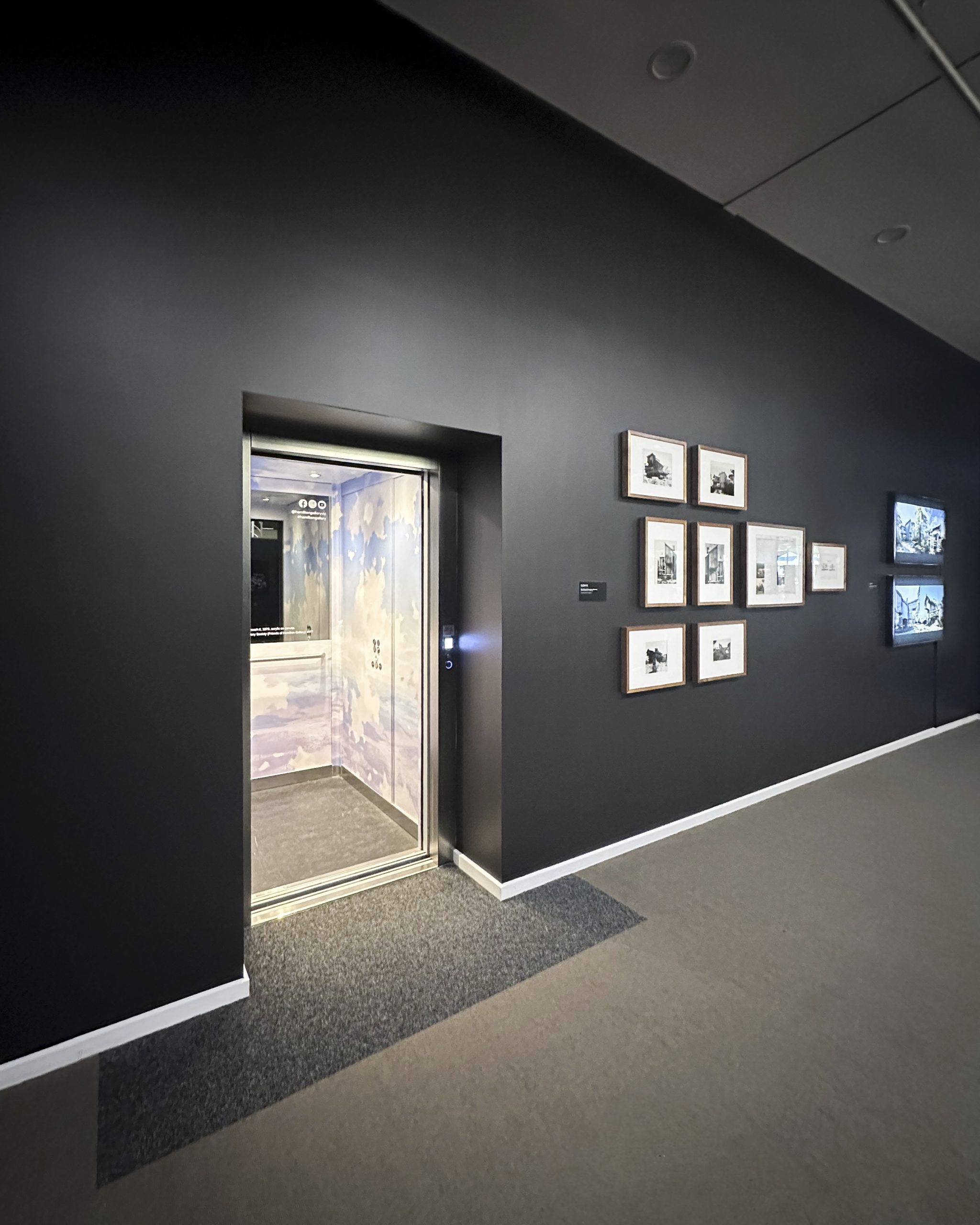 Open elevator in art gallery with framed artworks.