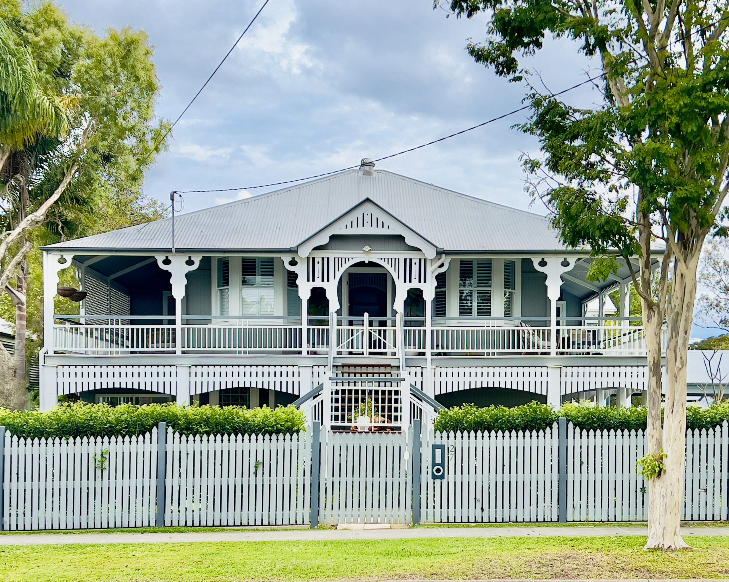 Keeping the Past Alive While Planning for the Future Classic Queenslander house with picket fence and veranda.