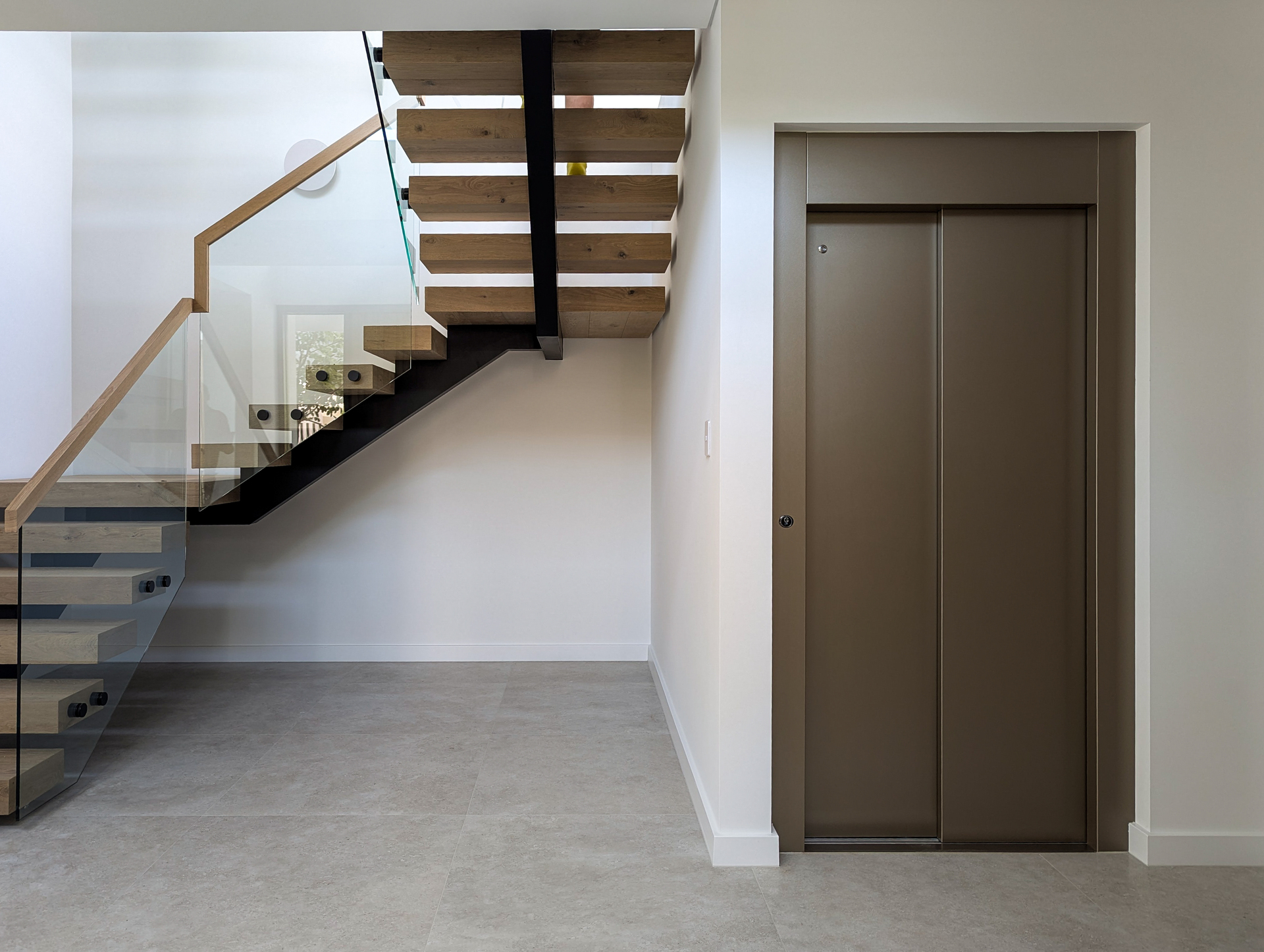 Modern staircase and lift in sleek interior design.