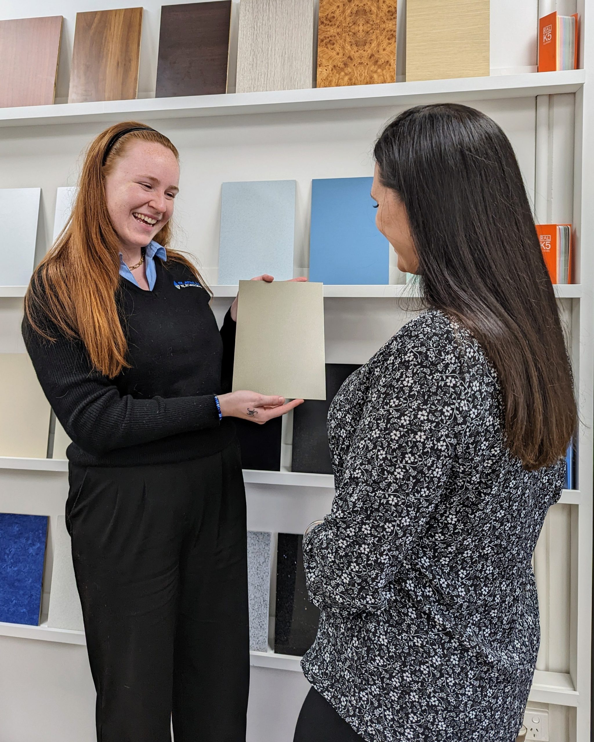 Two women discussing material samples in showroom.
