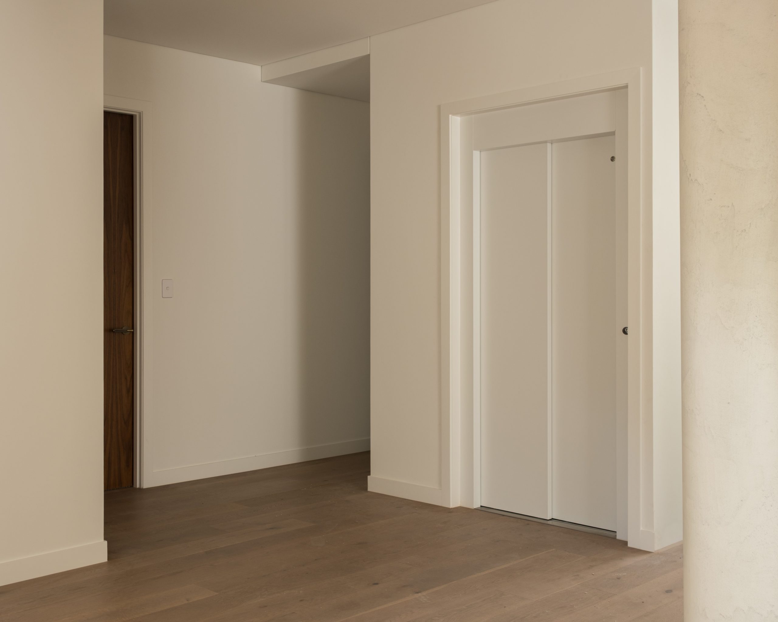 Minimalist interior with wooden flooring and white walls.