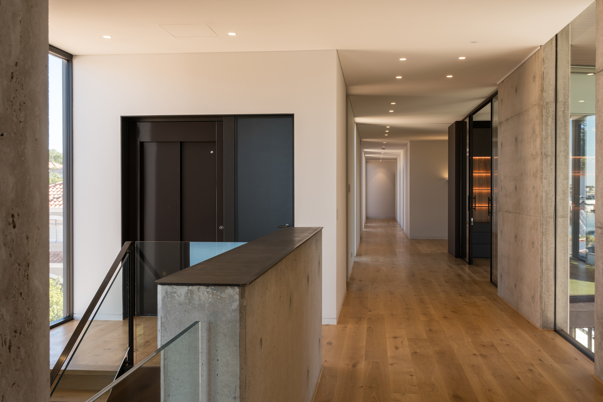 Modern hallway with wooden floors and concrete walls.