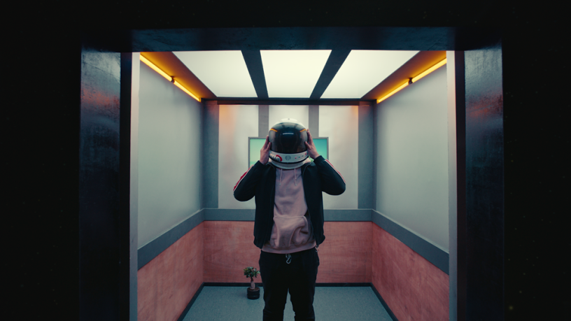 Raleigh Ritchie wearing spacesuit helmet in a elevator