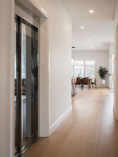 PEK Projects Modern home hallway with wooden floors and elevator.