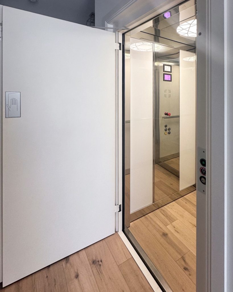 Open home lift with mirrored interior and timber floor