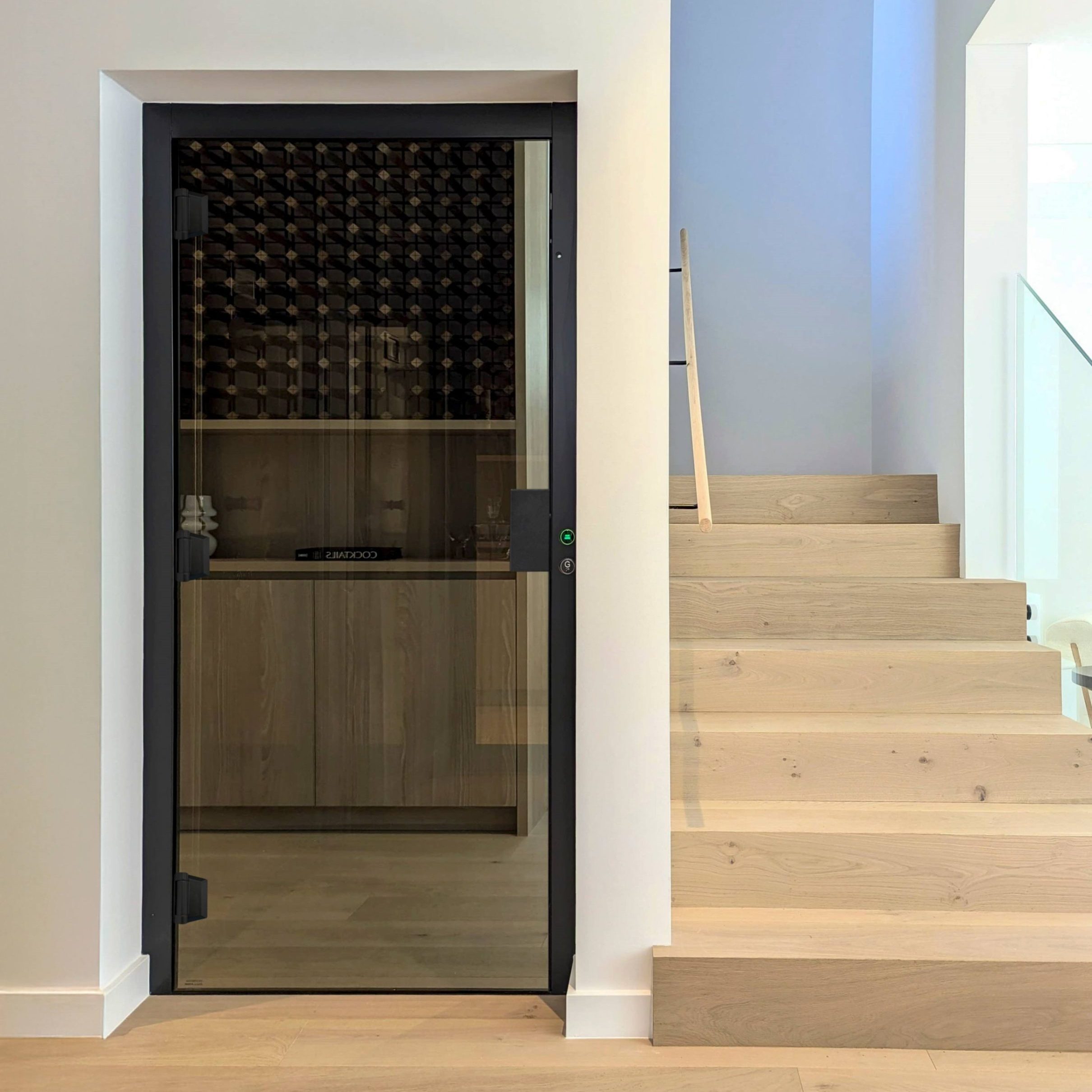 Glass wine cellar door beside wooden staircase